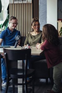 Blije gezichten. Achter de schermen bij de campagne fotoshoot voor HandicapNL bij lunchroom Beetje Bijzonder. Esther in gesprek met leuke vloggers Gijs en Ghislaine.