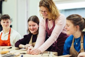 Meestergoudsmid Vivianne Veenemans begeleidt cursisten tijdens een workshop edelsmeden in haar atelier, terwijl zij sieraden met de hand maken.
