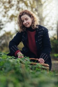 Wildplukker Marieke van Leersum verzamelt kruiden en planten in de natuur met een mand tijdens een fotoshoot in de uiterwaarden van Wageningen.