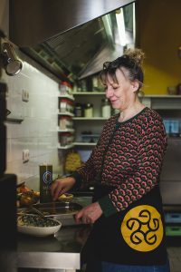 Judith Tesselaar van Vreemde Streken maakt vegan shoarma van oesterzwammen en specerijen in haar keuken. Ze werkt geconcentreerd aan een schaal met gekruide paddenstoelen. Ambachtelijke plantaardige voeding, lokaal geproduceerd en duurzaam, gefotografeerd voor StreekWaar in Wageningen.