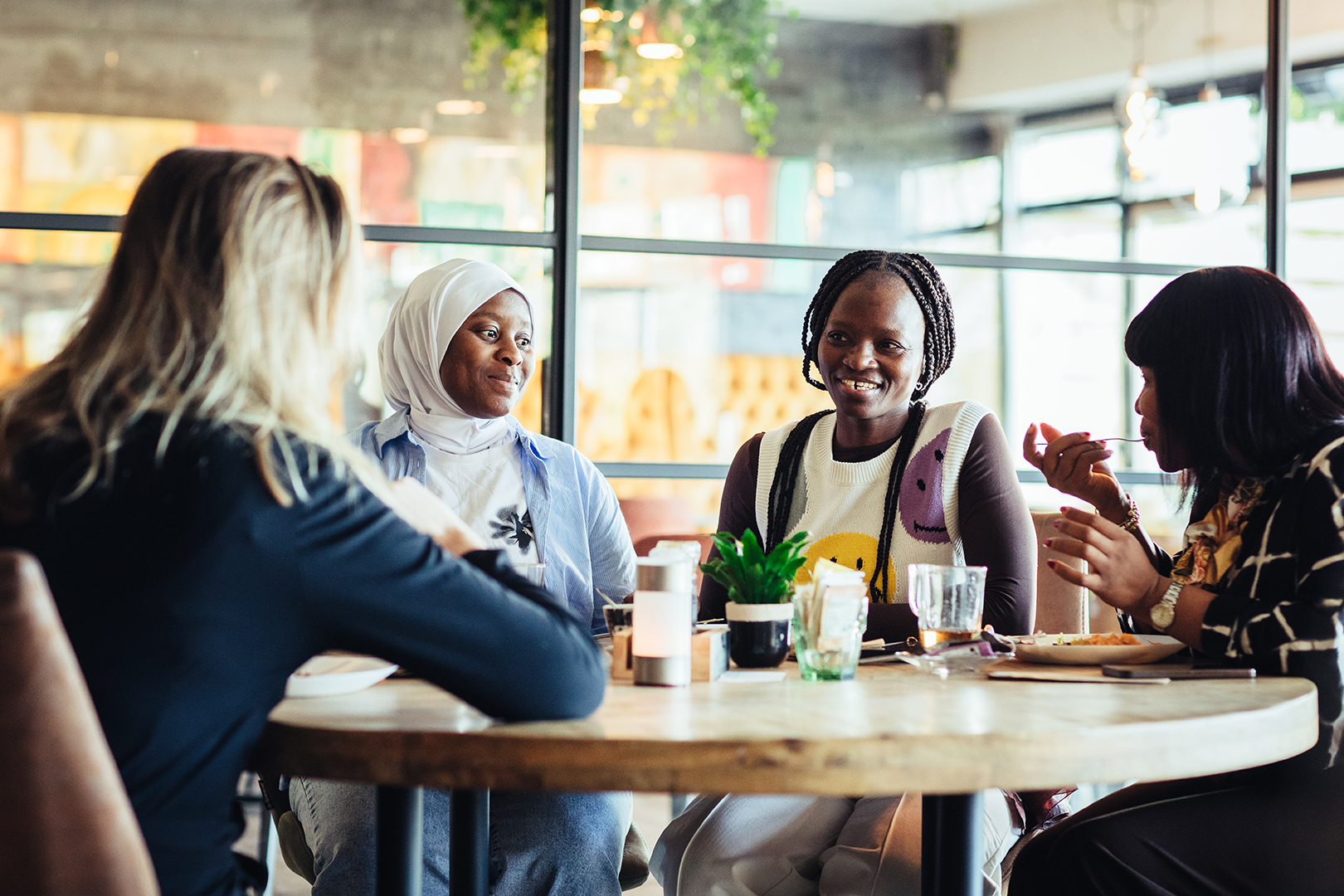 Een gemêleerd gezelschap van gasten met verschillende achtergronden zit samen aan tafel bij De Blaauwe Kamer in Wageningen, waar gesprekken, glimlachen en wereldse gerechten zorgen voor een warme en verbindende sfeer in het internationale buffetrestaurant.