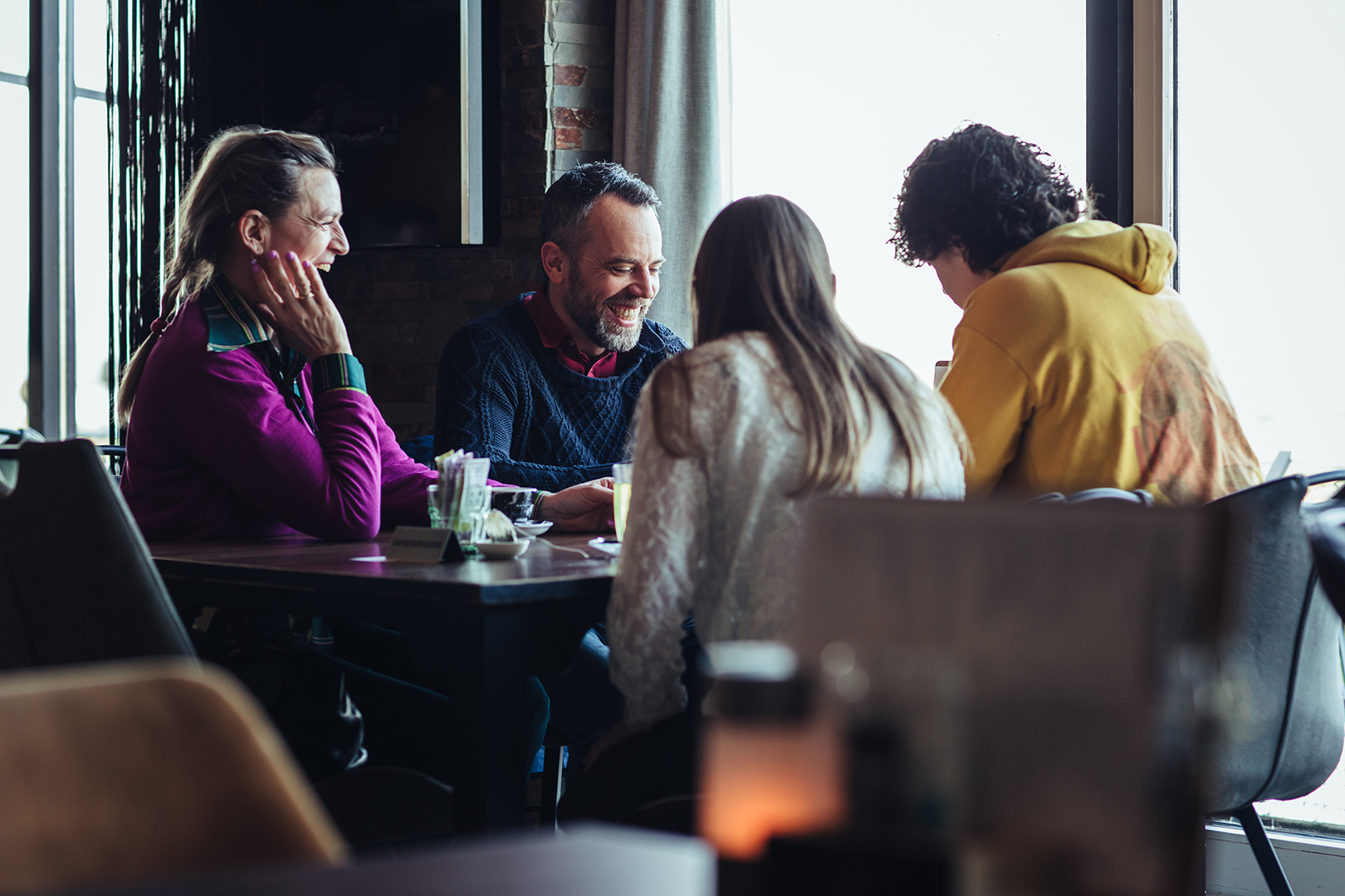 Gasten lachen samen breeduit aan tafel, bij een werelds buffet van De Blaauwe Kamer in Wageningen. Waar wereldse gerechten, gesprekken en ontmoeting samenkomen in een warme restaurantsfeer.