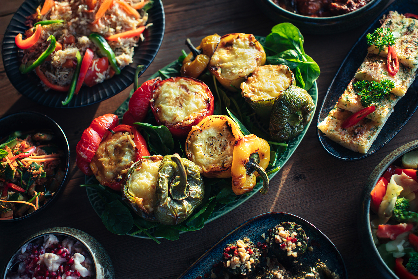 Kleurrijke gevulde paprika’s (Iraanse vegetarische dolme felfel) op een werelds buffet bij De Blaauwe Kamer in Wageningen, omringd door internationale gerechten vol kruiden, groenten en warme smaken uit het Midden-Oosten en Azië.